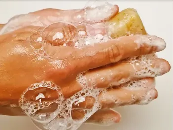 Close-up of hands creating a rich, bubbly lather with a bar of natural soap to demonstrate effective cleaning.