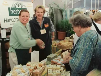 A photo from 2002 of our Founder LaRee Gilberg with her sister selling soap at a market booth