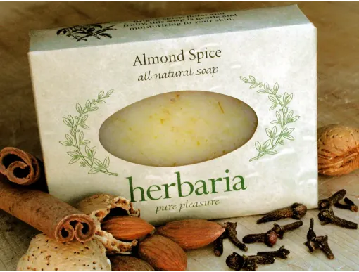 Almond Spice all-natural soap bar in Herbaria paper packaging surrounded by almonds, cloves, and a cinnamon stick.