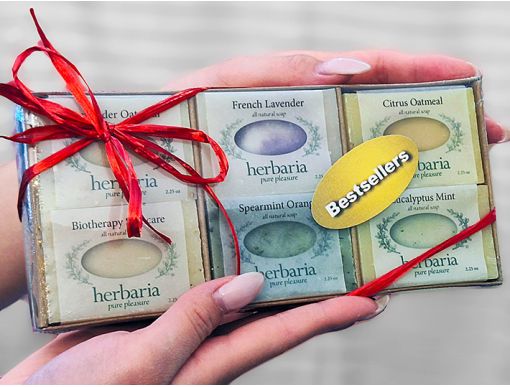 A hand-held Herbaria Soap gift set in a decorative cardboard tray containing six best-selling soap half-bar varieties, perfect for a natural skincare gift.