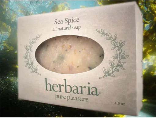 A paper wrapped bar of Sea Spice soap from Herbaria floating in seaweed underwater.