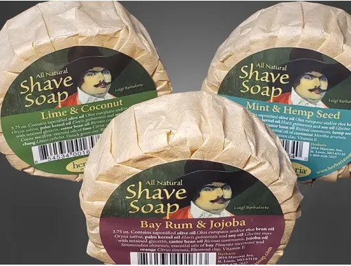 A set of 3 round bars of Herbaria all-natural shave soaps featuring the embossed Herbaria logo on a rustic brown paper wrap.