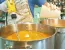 Blake mixing soaps and the added essential oils in a large stainless steel pot with an electric hand-held mixer.