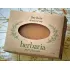 A bar of Herbaria Bay Rum all-natural soap in a kraft paper label with an oval cutout, displayed on a vintage map background