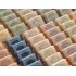 Rows of various Herbaria handmade all natural half-bar soaps view fromt he top down. Soaps are displayed on a wooden shelf.
