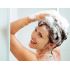 A woman joyfully shampooing her hair with Herbaria shampoo bars in the shower.