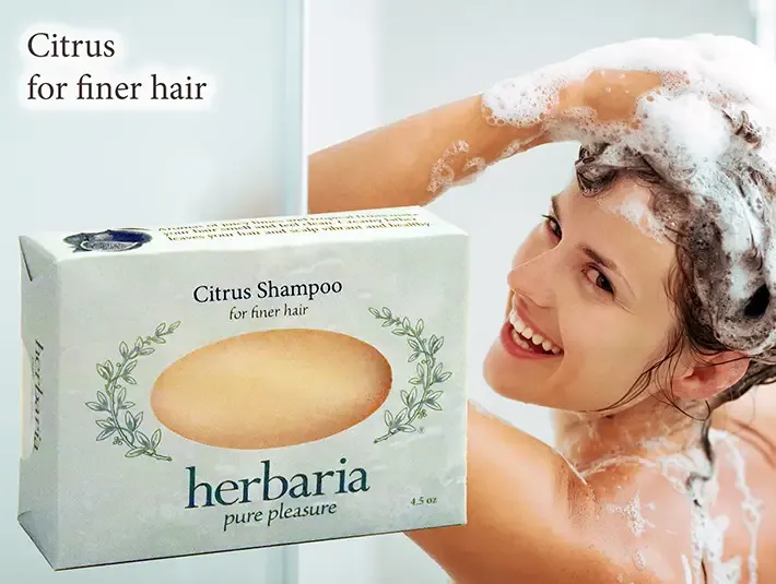 Herbaria Citrus Shampoo bar for thicker hair with a woman lathering her hair in the shower.