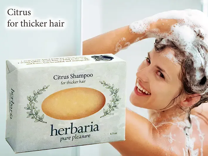 Herbaria Citrus Shampoo bar for thicker hair with a woman lathering her hair in the shower.