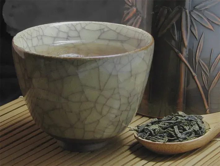 green tea cup and spoon of dried tea leaves