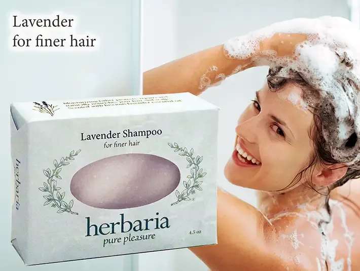 Herbaria Lavender Shampoo bar for finer hair with a woman lathering her hair in the shower.