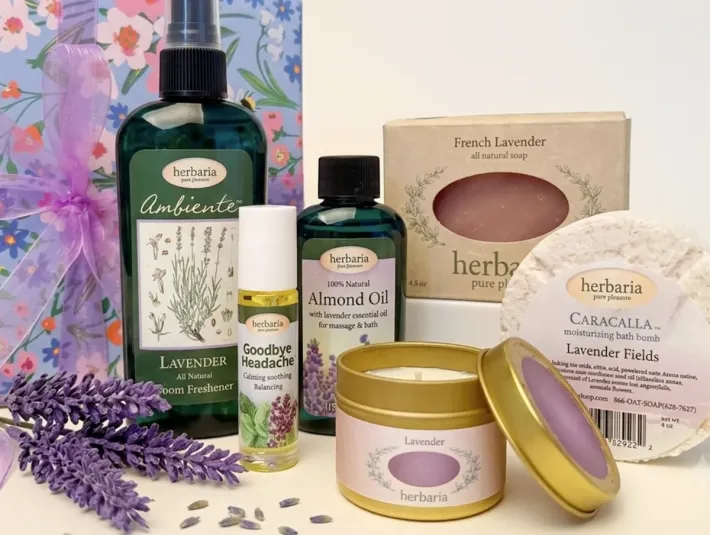 Herbaria natural lavender gift set featuring handmade soap, candle, bath bomb, almond oil, room spray, and headache oil in a floral wrapping paper.