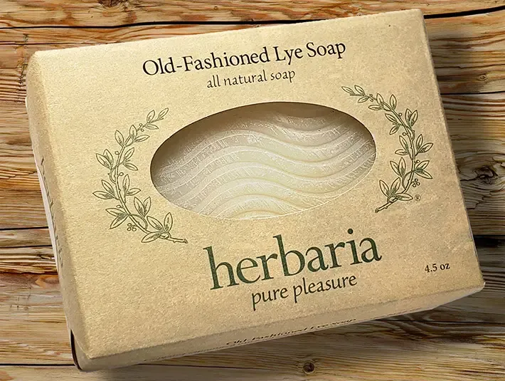 Handmade old-fashioned lye soap bar with wavy pattern wrapped in paper on a wooden surface.