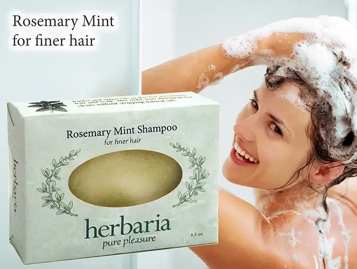 Herbaria Rosemary Mint Shampoo bar for finer hair with a woman lathering her hair in the shower.