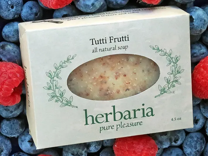 A bar of Herbaria Tutti Frutti soap next to fresh berries, highlighting its natural fruit-based ingredients and essential oils.