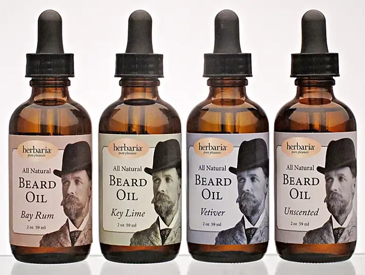 Herbaria handmade natural beard oil collection featuring four amber dropper bottles of unique essential oil scents.