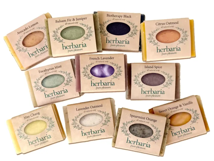 A group of Herbaria's 11 hotel-sized soaps spread out on a white background.